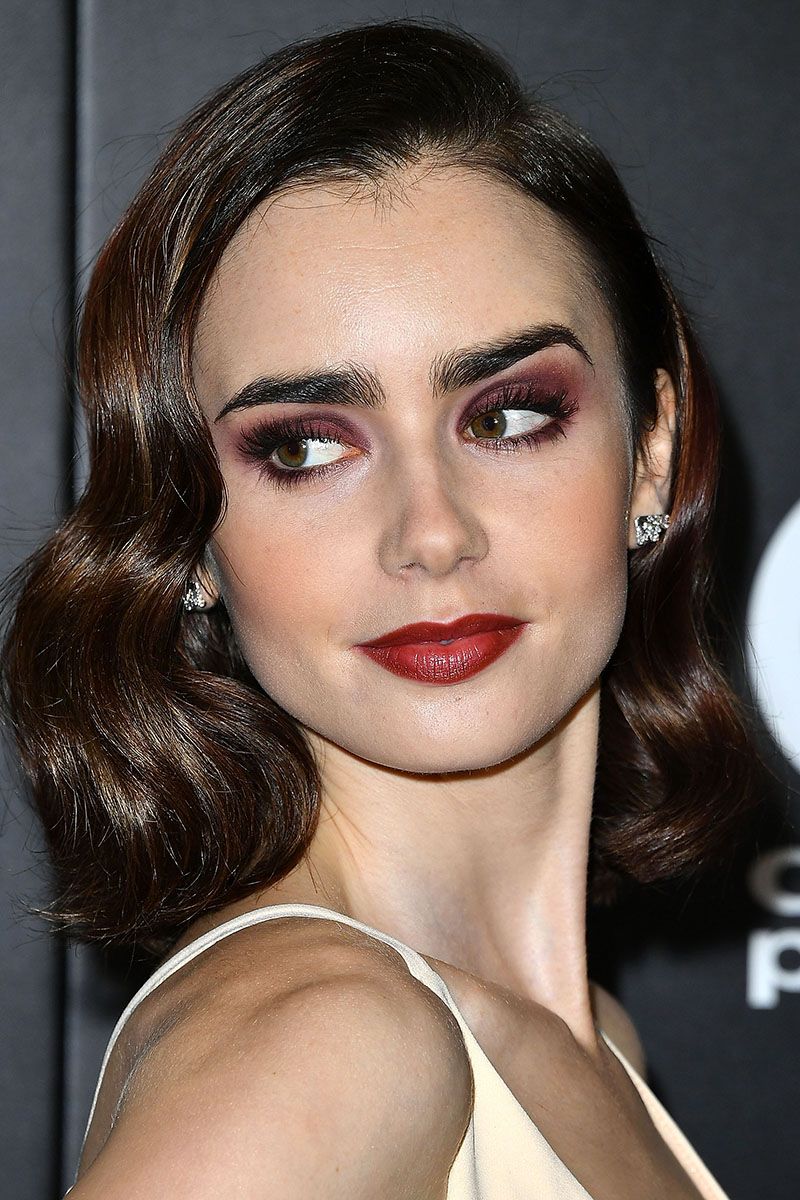 <p>Lily Collins makes a case for wearing color all-over: brick-red on the lips, peach on each cheek, and smoky plum shadow buffed across both lids.</p>
