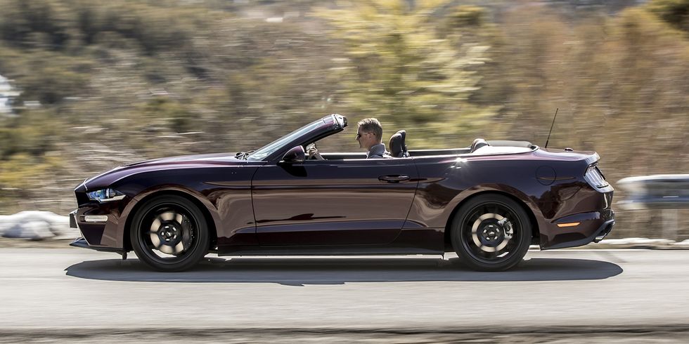 ford mustang convertible color burdeos en carretera, vista lateral