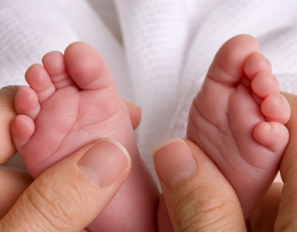 un color de piel azulado en los pies de un recién nacido, como los que se ven en la foto sujetos por unas manos de adulto, indica que la circulación sanguínea aún se está estabilizando