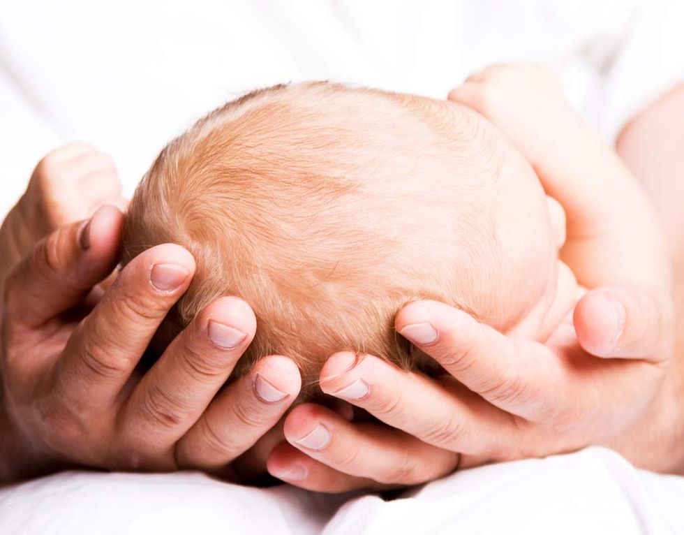 signo de alarma es un tono de piel grisáceo en un recién nacido, como el de la foto cuya cabeza aparece sujeta por las manos de su padre