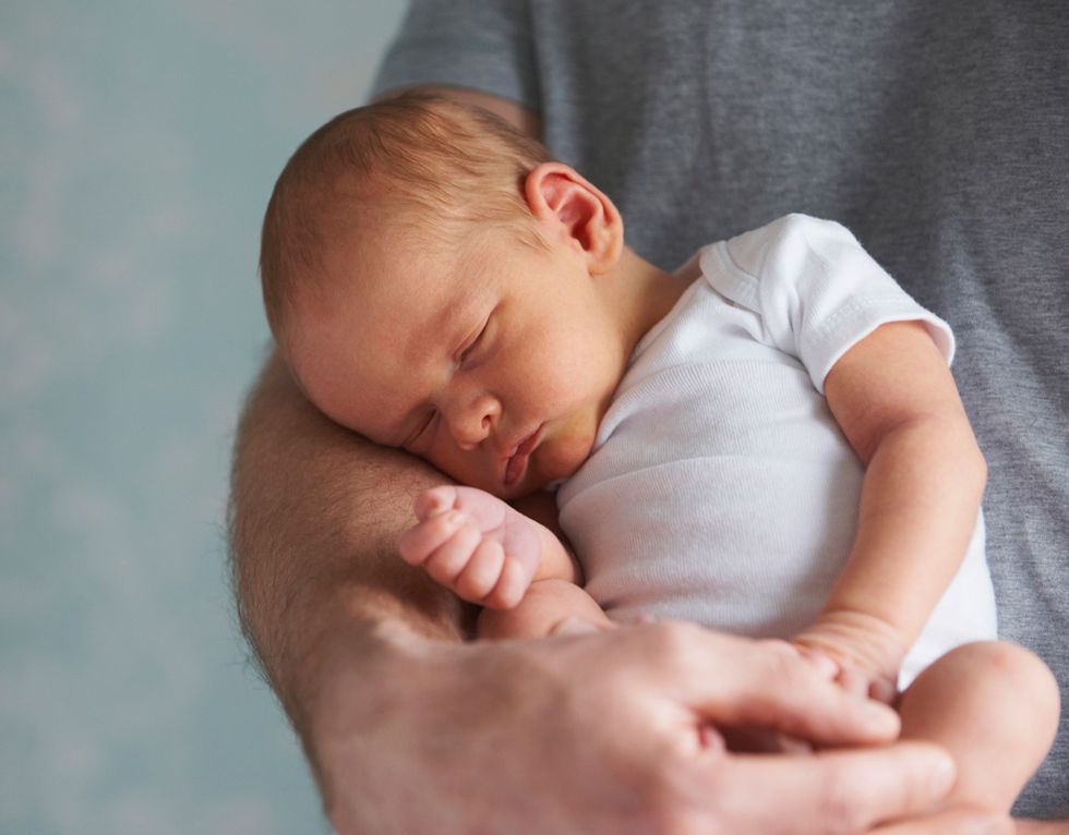 recién nacido durmiendo en brazos de su padre