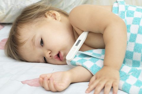 aprender cómo actuar ante un bebé con fiebre, como el de la foto que está tumbado con el termómetro en la axila