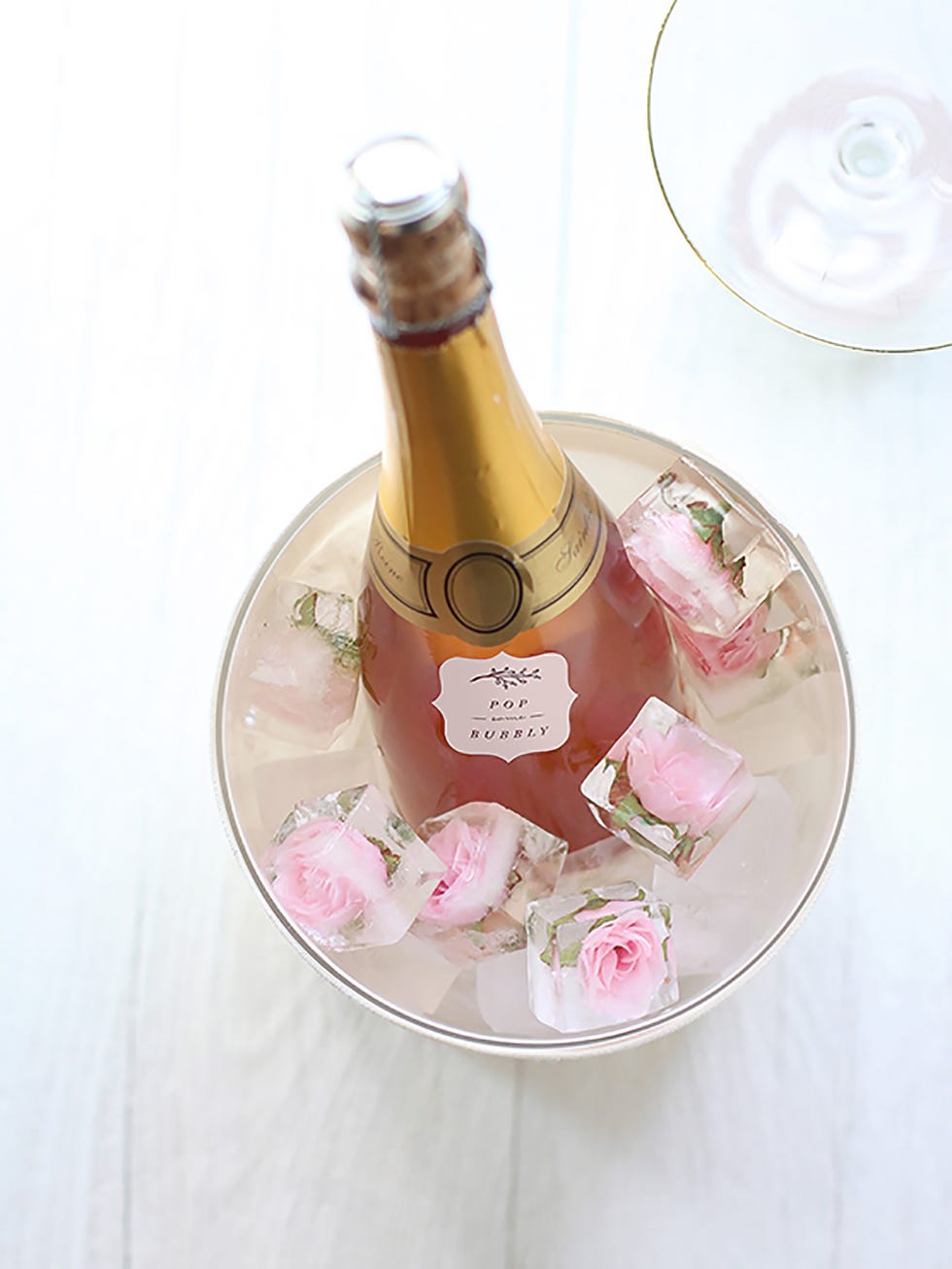 botella de champán rosa en cubitera con rosas