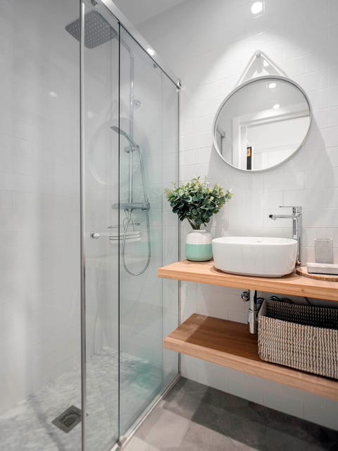 baño pequeño con mampara de cristal y baldas de madera