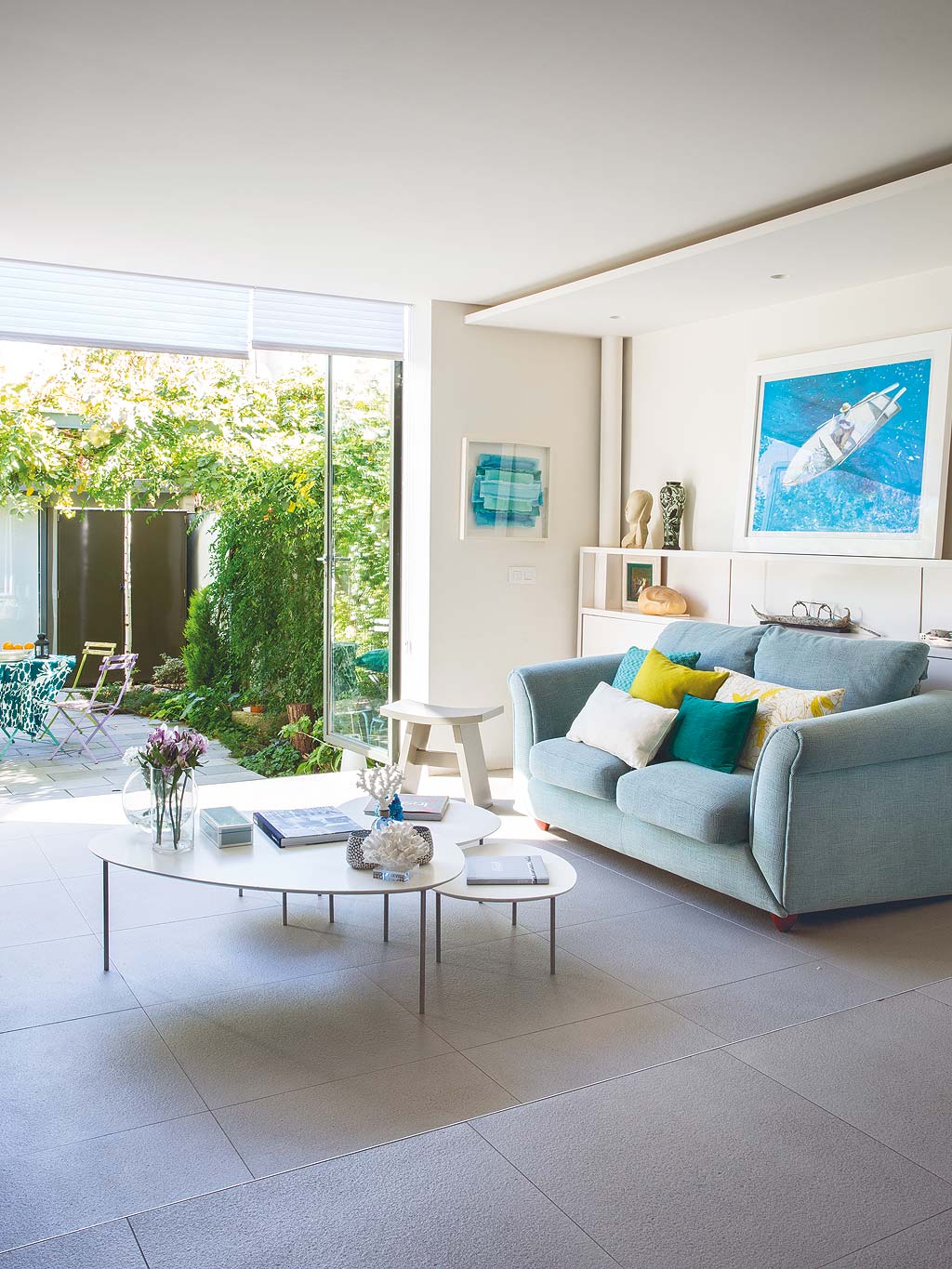 salón de verano con sofá azul abierto al jardín