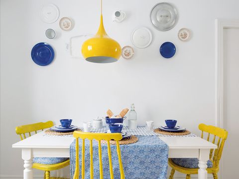 mesa de comedor blanca con sillas amarillas y mantel estampado azul