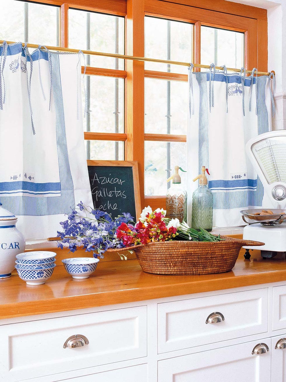 cocina rústica con encimera de madera y visillos blanco y azul