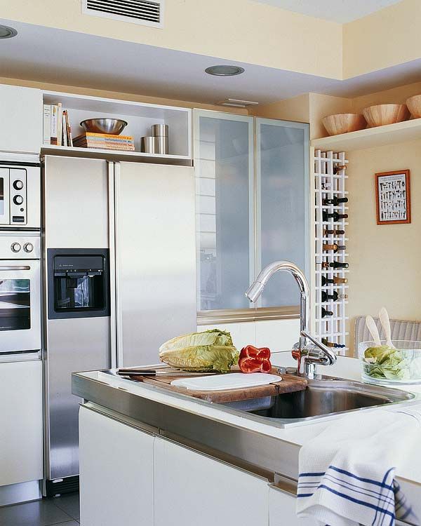 Isla de cocina con armarios despenseros y columna de electrodomésticos  integrados en cerezo y metal