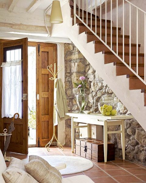 recibidor con pared de piedra y consola bajo la escalera