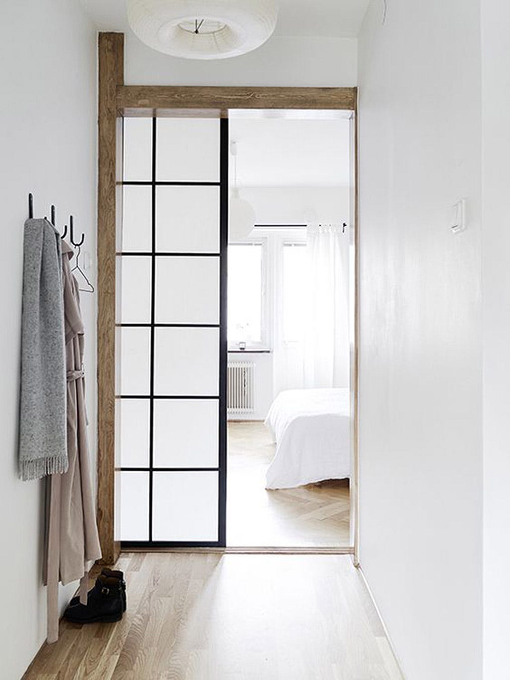 puerta corredera panelada para dejar pasar la luz natural al distribuidor de la casa