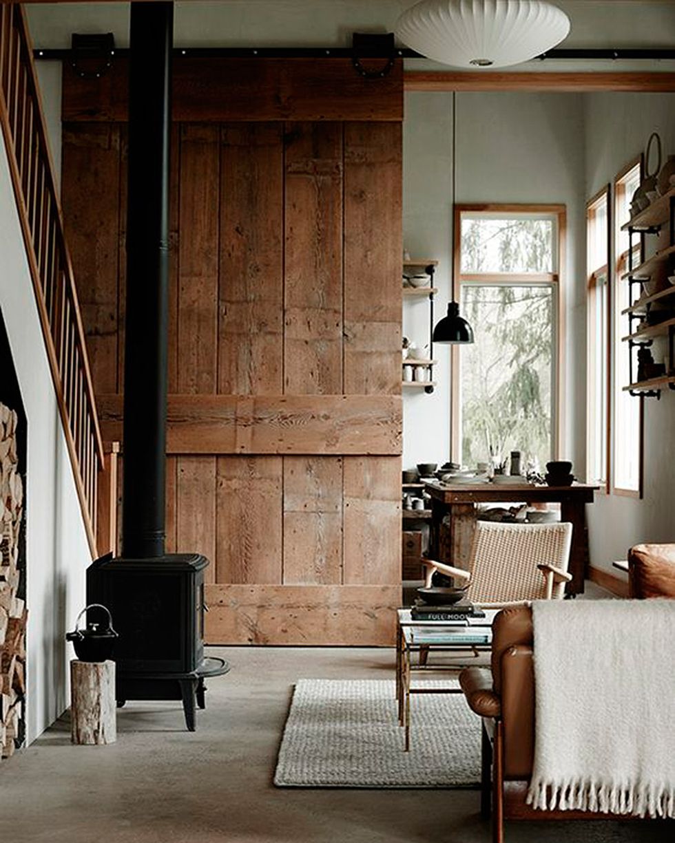 puerta corredera estilo granero sobre grandes rieles en una casa de campo de estilo industrial y rústico