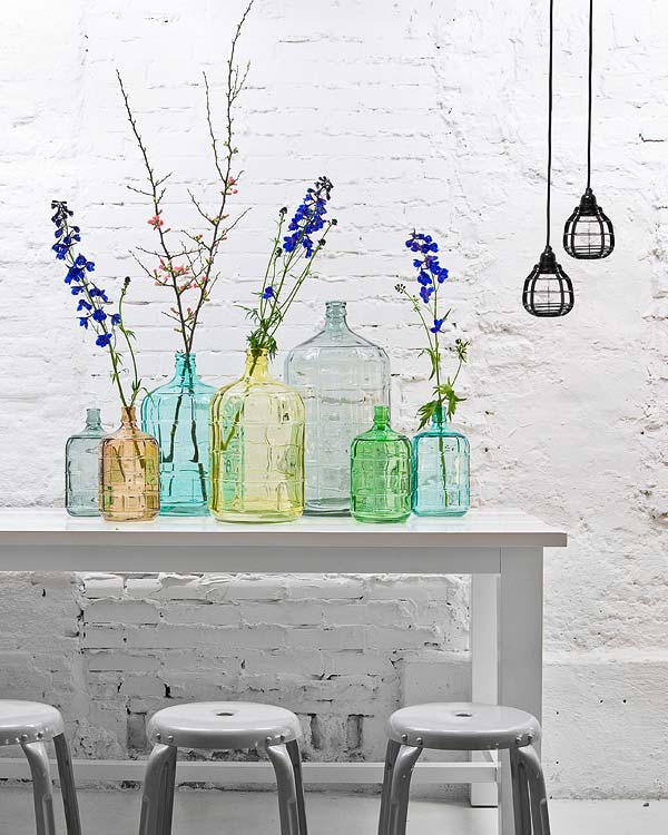 mesa decorada con botellas y damajuanas verdes y azules