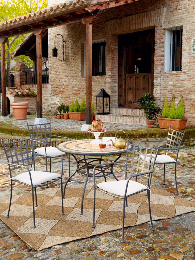 patio con comedor exterior y alfombra de yute a rombos