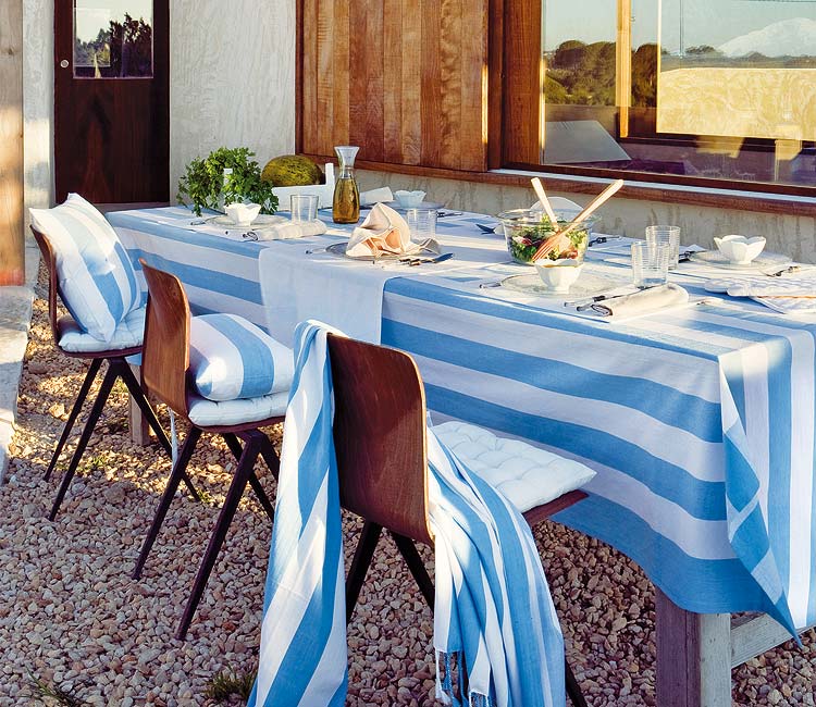 mesa en el jardín con mantel azul a rayas