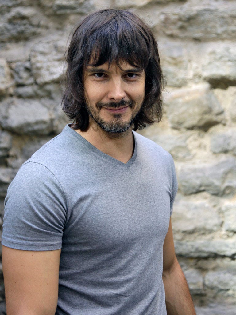 Mouth, Facial hair, Sleeve, Shoulder, Stone wall, T-shirt, Beard, Chest, Muscle, Neck, 