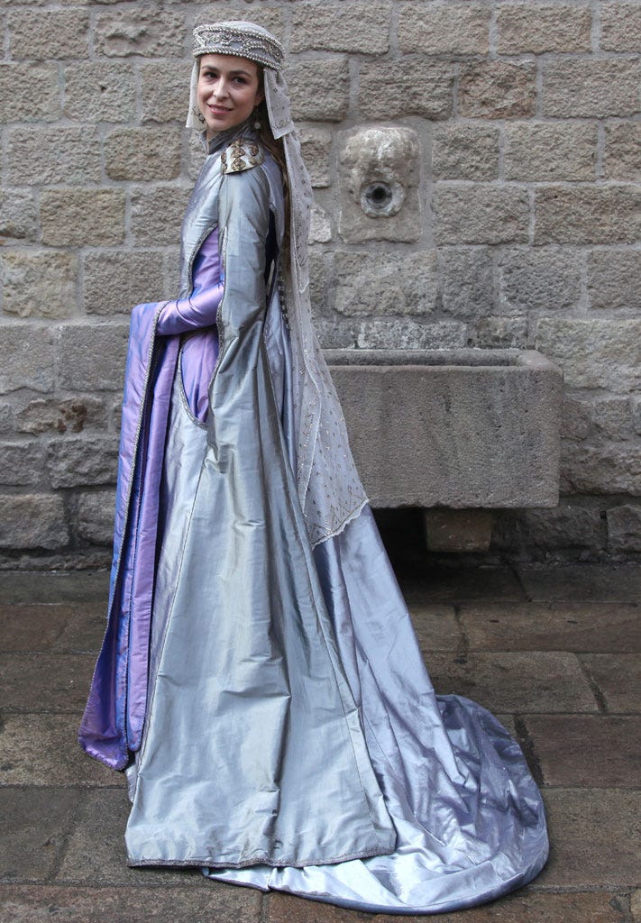 Purple, Stone wall, Dress, Gown, Costume, Costume design, Street fashion, Brick, Tradition, Fashion design, 