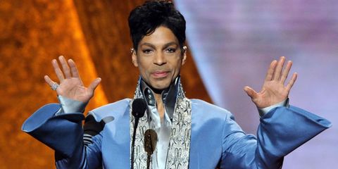 Prince stands on the stage at an awards show wearing a blue bedazzled jacket