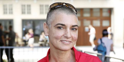 Sinead O'Connor in a red shirt smiles at the camera