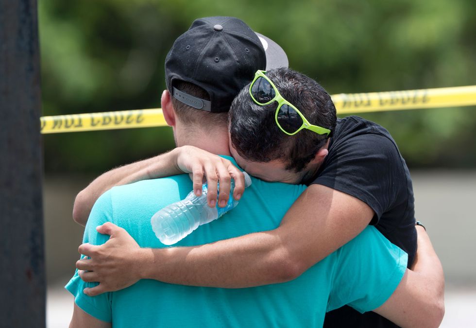 Supported by a friend, a man weeps for victims of the mass shooting just a block from the scene in Orlando.