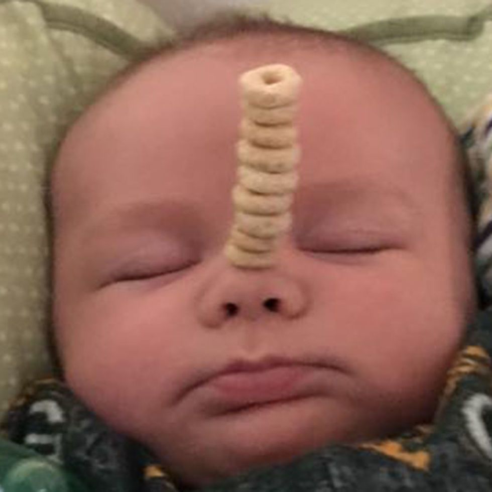 a sleeping baby with cheerios stacked on its nose