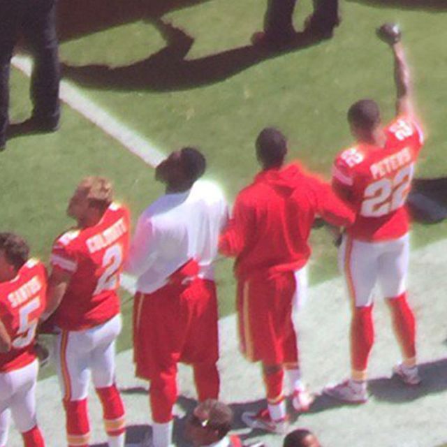 Peters raises his right fist and interlocks his arm with other Kansas City Chiefs players