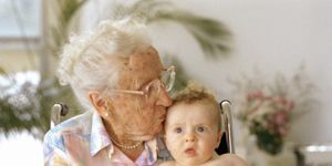 grandma kisses her grandson and he does not enjoy it