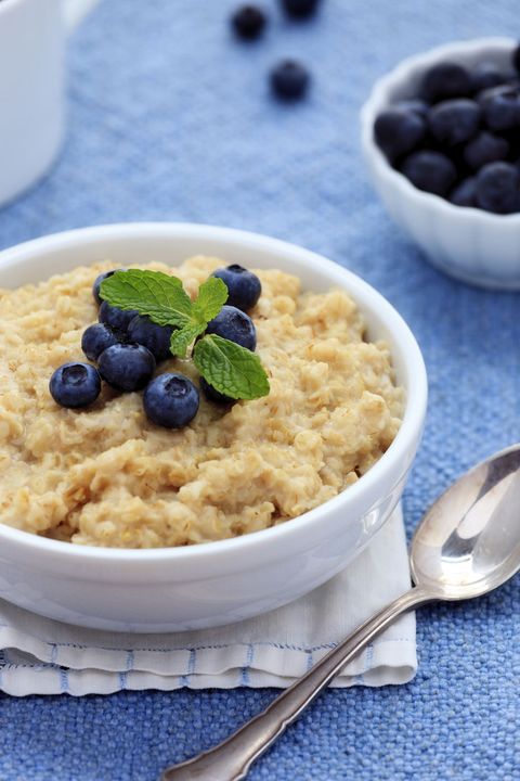 a bowl of oatmeal topped with blueberries on a blue tablecloth, a good housekeeping pick for a healthy weight loss food