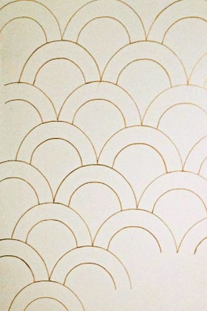 First, outline the arch of the larger scallop repeatedly on your wall using the metallic pen, connecting the arches on the sides. Create a second row beneath the first, staggering them so they fall between the arches of the previous row. Continue until your wall is covered, then go back and trace the entire form of the smaller scallop within each of the larger scallops.