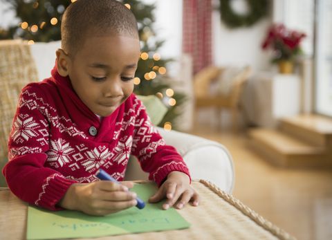 black boy writing letter to santa while wearing a red and white sweater