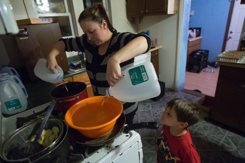 Oct. 1, 2015 - Flint, Michigan, U.S. - LEE ANNE WALTERS, of Flint, pours gallons of bottled water into a bucket and pan to warm up for her two twin sons to take a weekly bath as her son GAVIN WALTERS 4, looks on on. Walters uses 8-10 gallons of bottled water to avoid her children's exposure to the Flint drinking water that contains high levels of lead since the city switched from getting their water from Detroit to use water from the Flint River. 'My family will never drink from a tap again. Never ever it's too scary,' Walters said. 
