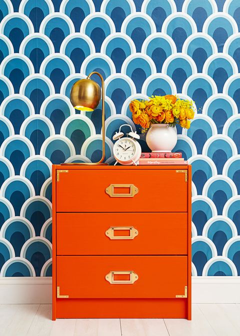 bedroom ideas, orang dresser against patterned blue and white backdrop with flowers and a lamp on top