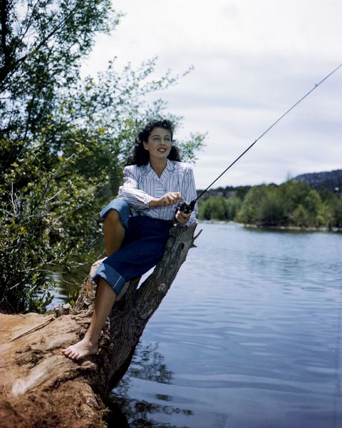 Gail Russell (1924-1961), wearing white blouse with blue stripes, and rolled up denim jeans, holding a fishing rod, circa 1955. (Photo by Silver Screen Collection/Getty Images)