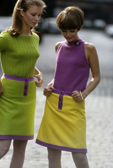 Two unidentified models, one in a green sweater and green skirt and the other in a purple sleeveless top and yellow skirt, pose together, New York, New York, September 1966. Both skirts feature purple trim. (Photo by Susan Wood/Getty Images)
