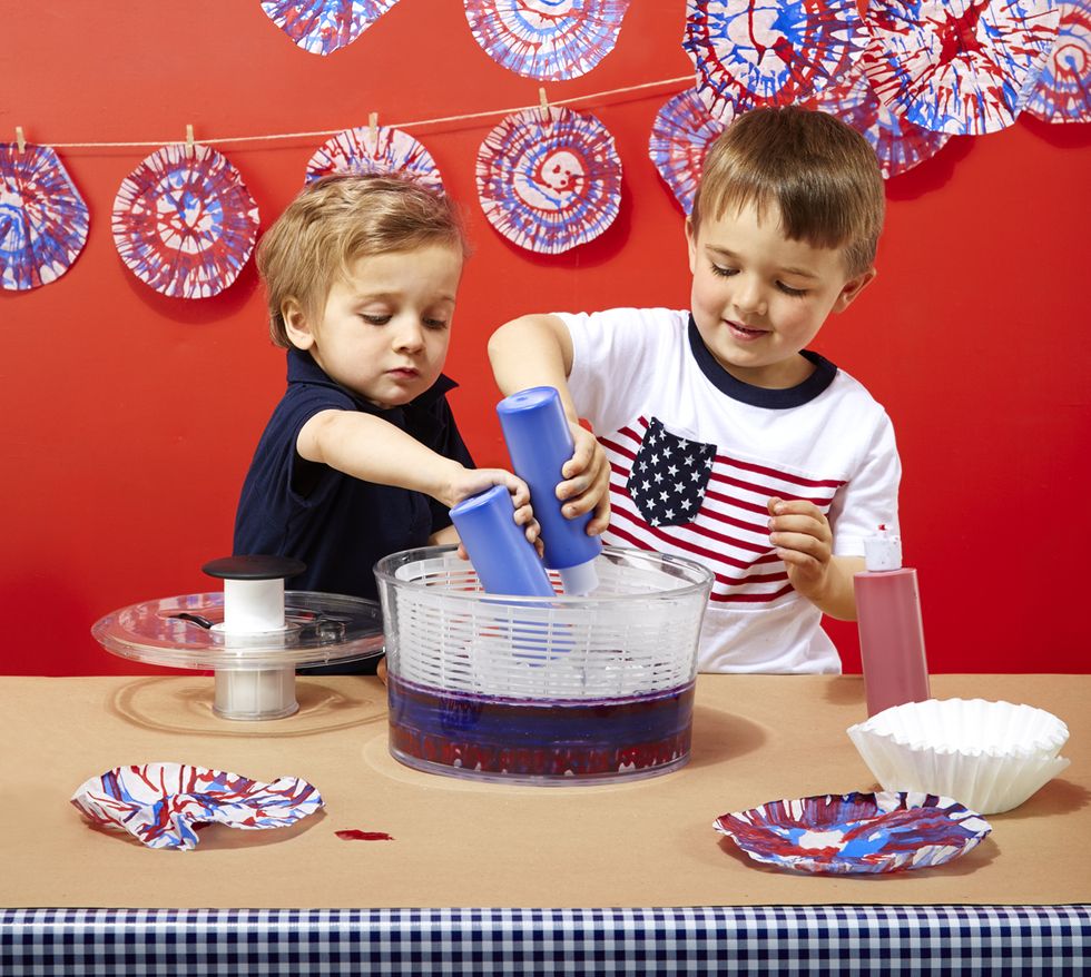 two kids add colors into a spin art machine made from a salad spinner the project is a good housekeeping pick for best activities for kids