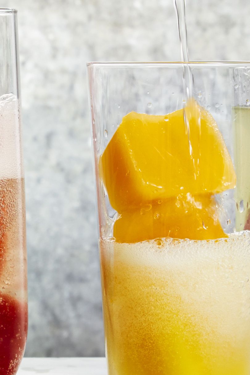 champagne flute with peach puree ice cubes and prosecco