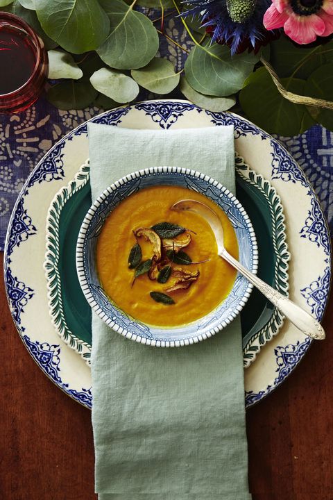 a bowl of pumpkin soup with sage leaves on top