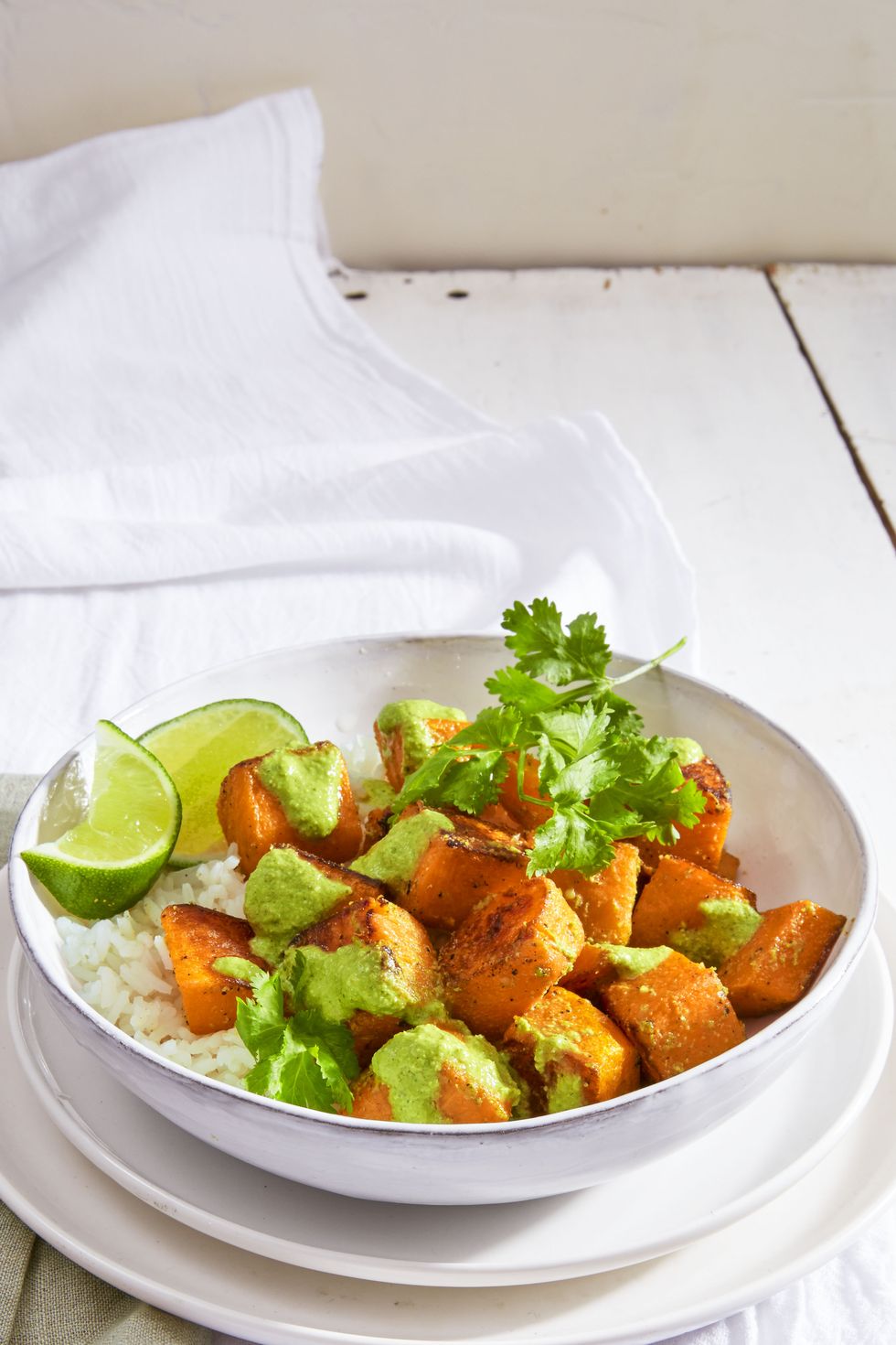 roasted squash over white rice with lime wedges in a white bowl