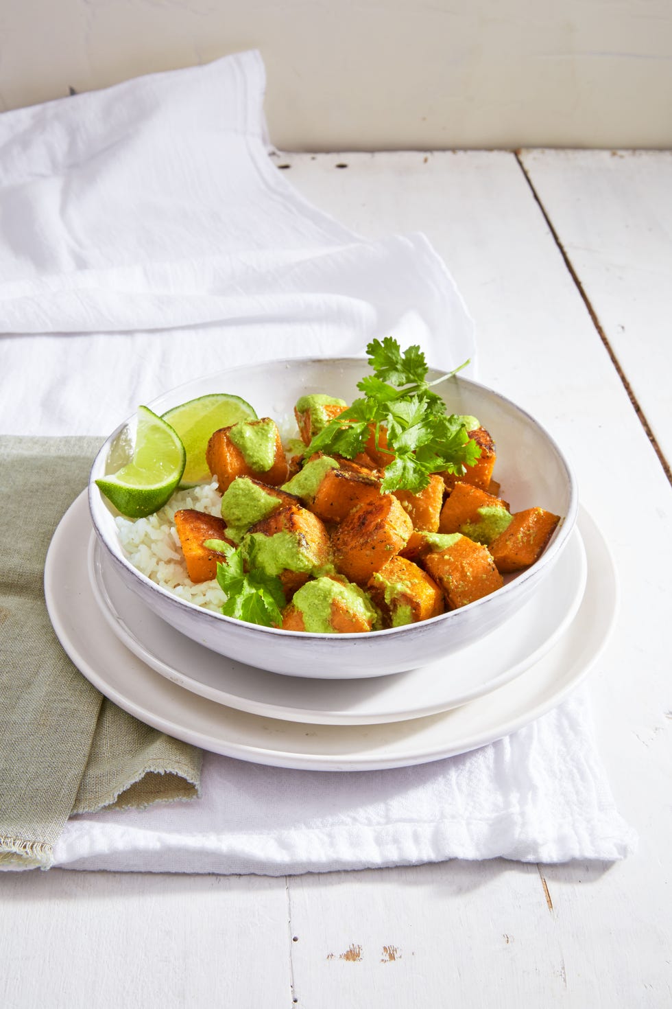roasted squash over white rice with lime wedges in a white bowl