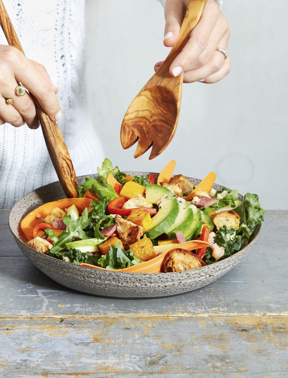 arugula kale harvest salad in a bowl with serving utensils