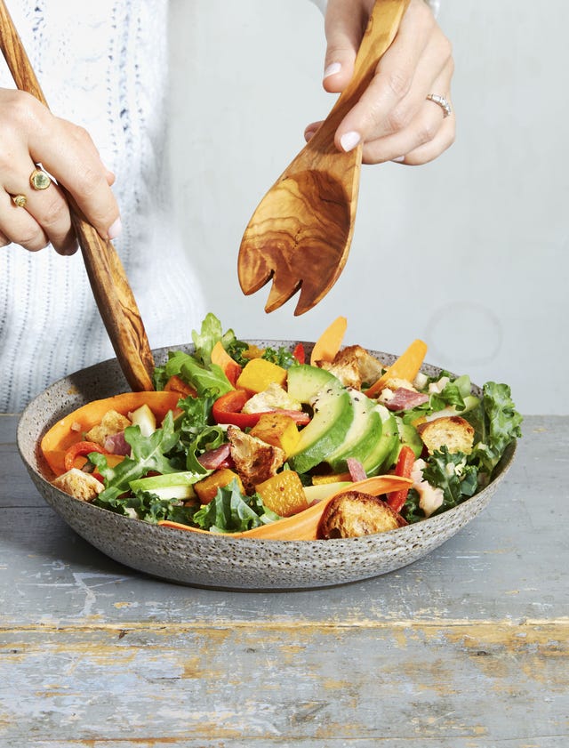 arugula kale harvest salad in a bowl with serving utensils