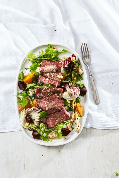 steak salad with charred green onions and beets on a white plate