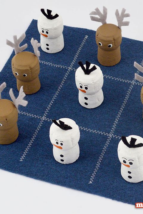 wine corks painted like reindeer and snowmen one a blue felt board