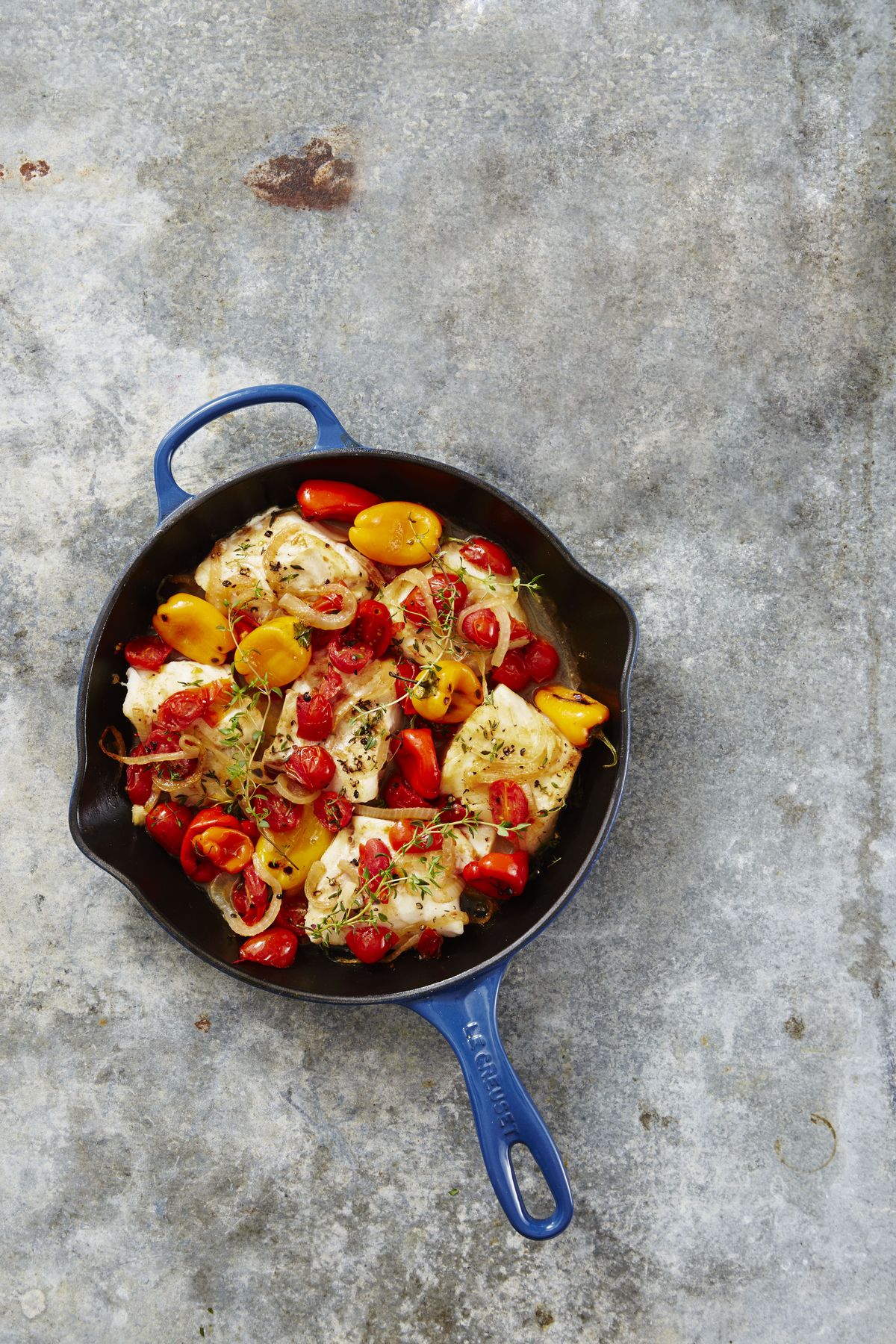 baked cod with peppers and tomatoes in a cast iron pan