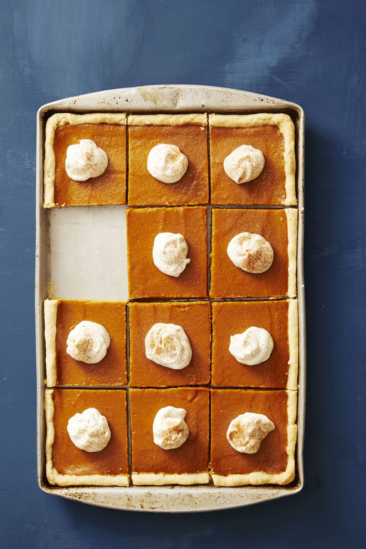 pumpkin slab pie cut into squares and served with whipped cream