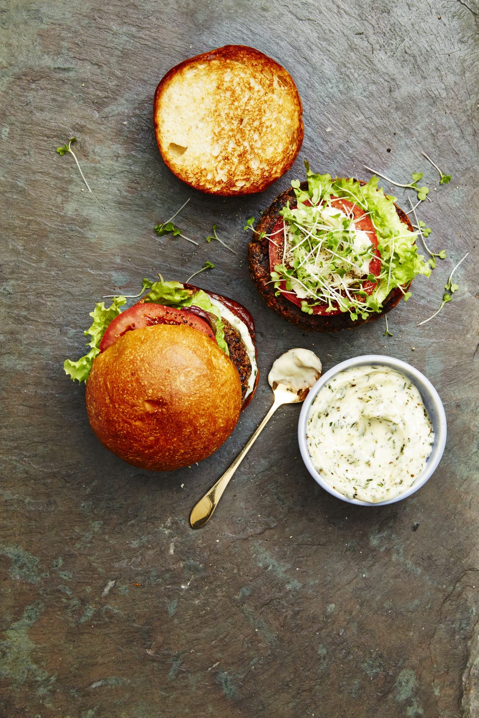veggie burgers topped with sliced tomatoes, sprouts and creamy sauce