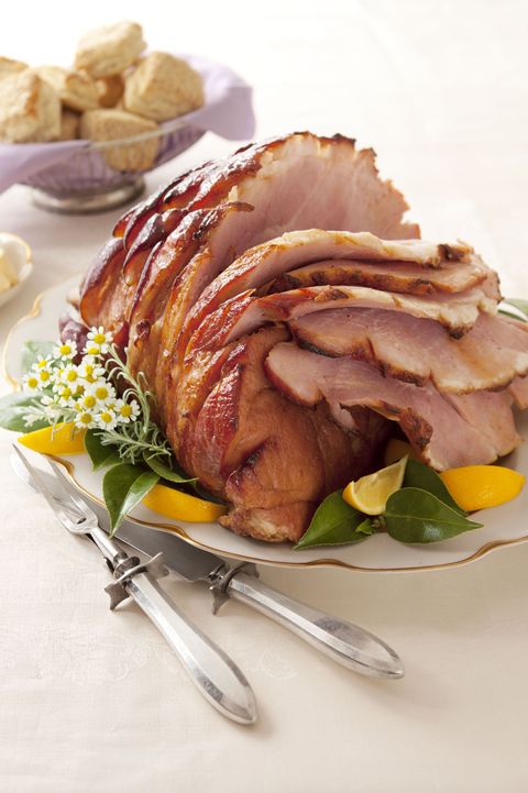 ham with bee sting glaze served with slices of lemon on a white plate