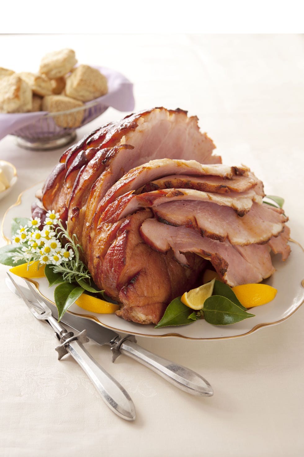 ham with bee sting glaze served with slices of lemon on a white plate
