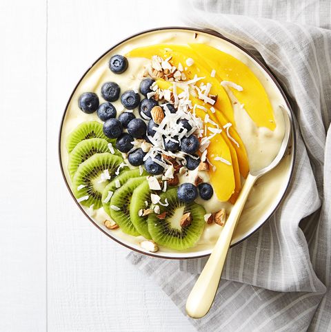tropical smoothie bowl with mango, blueberries, kiwi, and coconut shavings