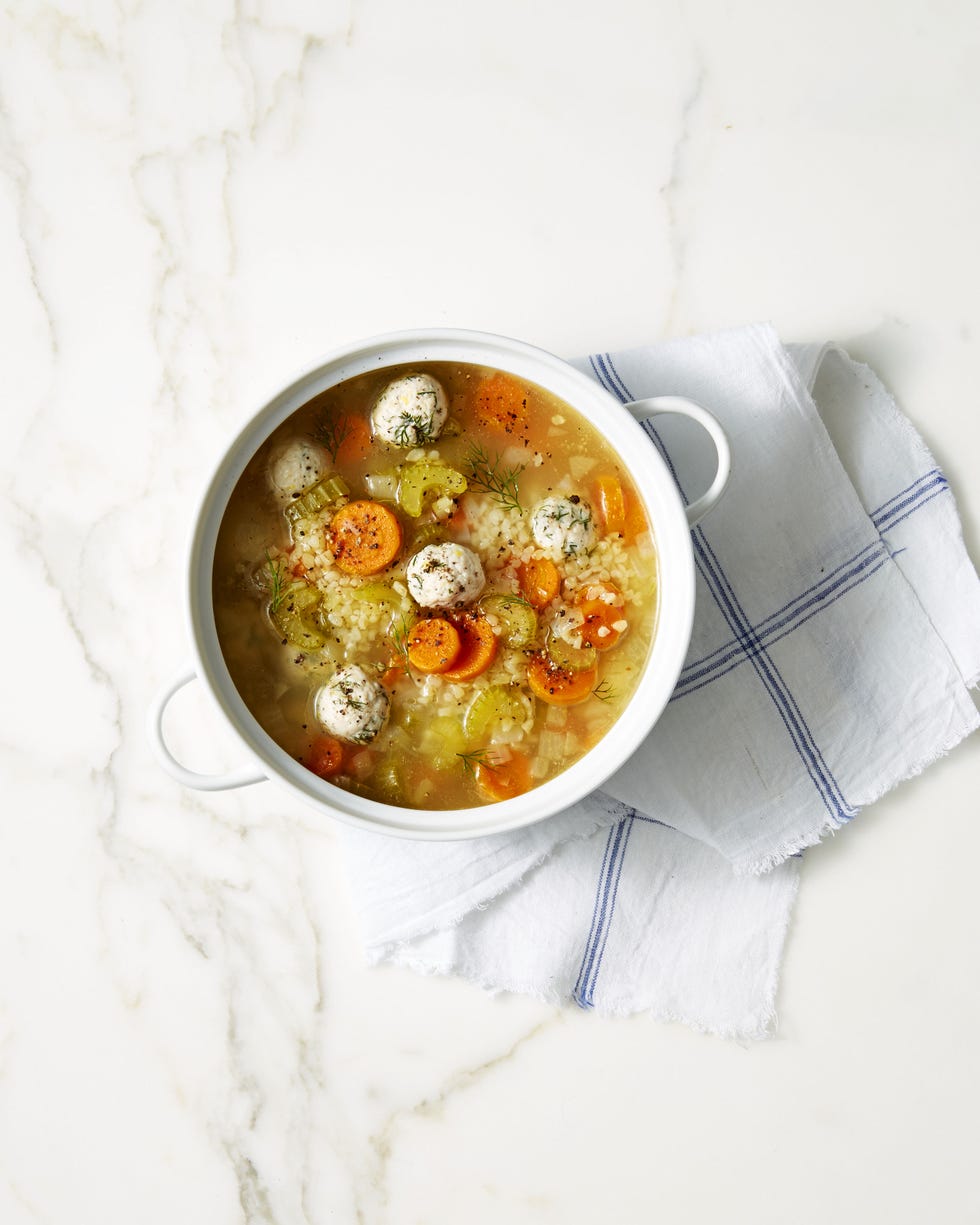 lemon dill chicken meatball soup with sliced carrots in a white pot
