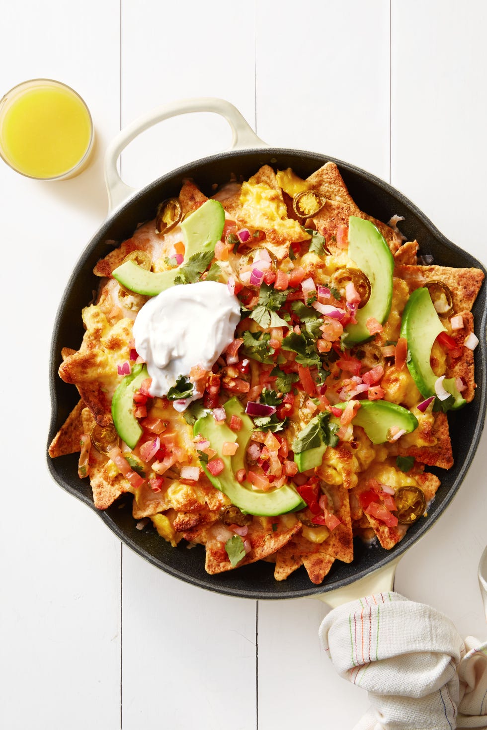 mexican breakfast chilaquiles with avocado and sour cream served in a cast iron dish